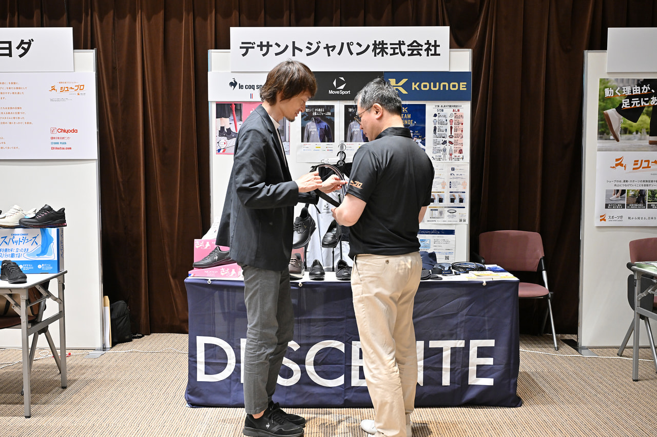 河合純一スポーツ庁長官がデザントジャパン株式会社のブースで説明を受けている画像